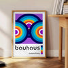 Poster mit abstraktem Bauhaus geometrischem Design in Primärfarben - neben einem runden Beistelltisch aus Holz mit Büchern