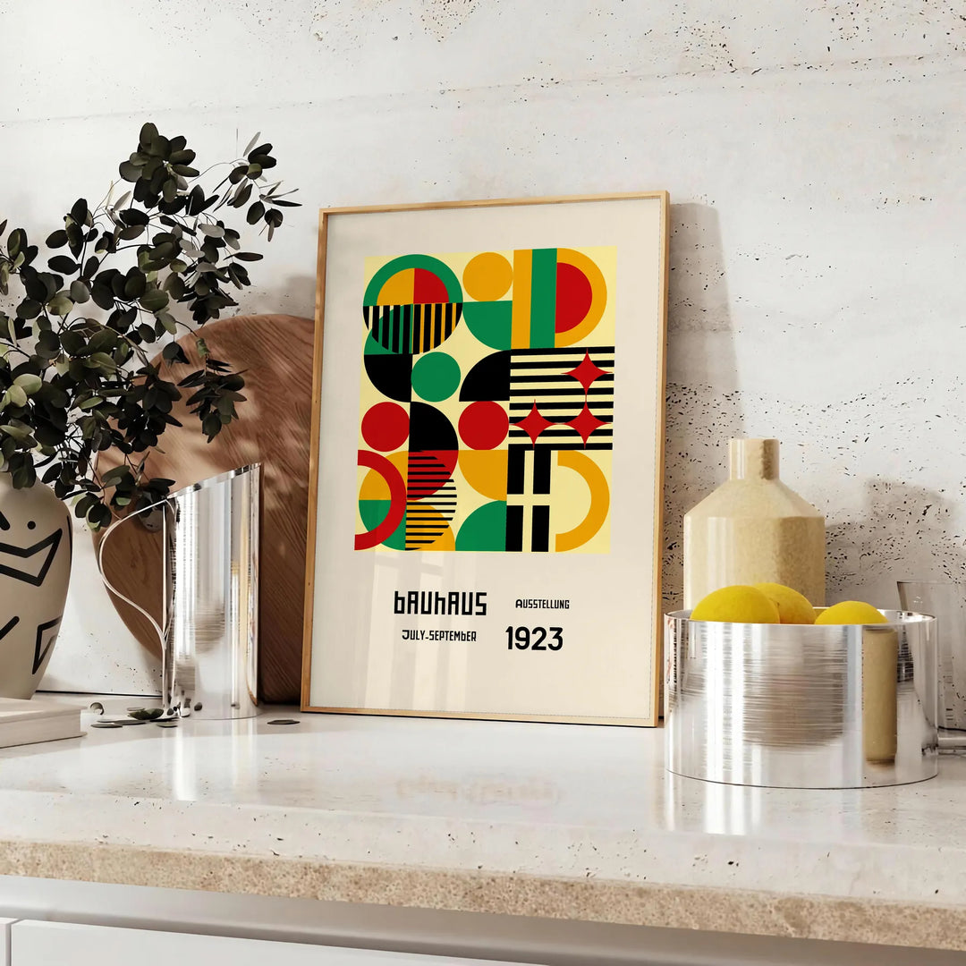 Poster Bauhaus con composizione geometrica astratta in verde e rosso intensi - su un piano con eucalipto e una ciotola di limoni