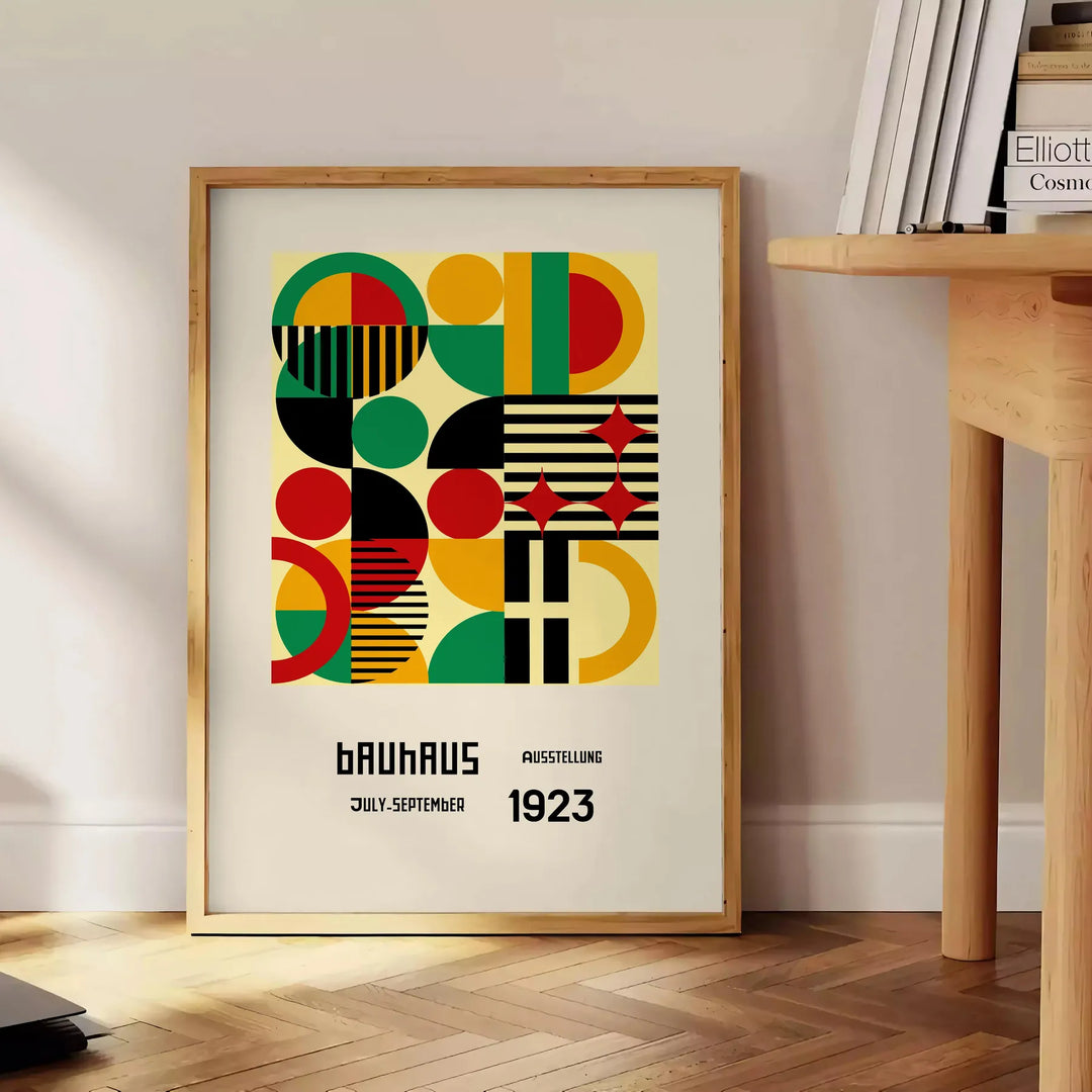 Poster Bauhaus con composizione geometrica astratta in verde e rosso intensi - accanto a un tavolino rotondo in legno con libri