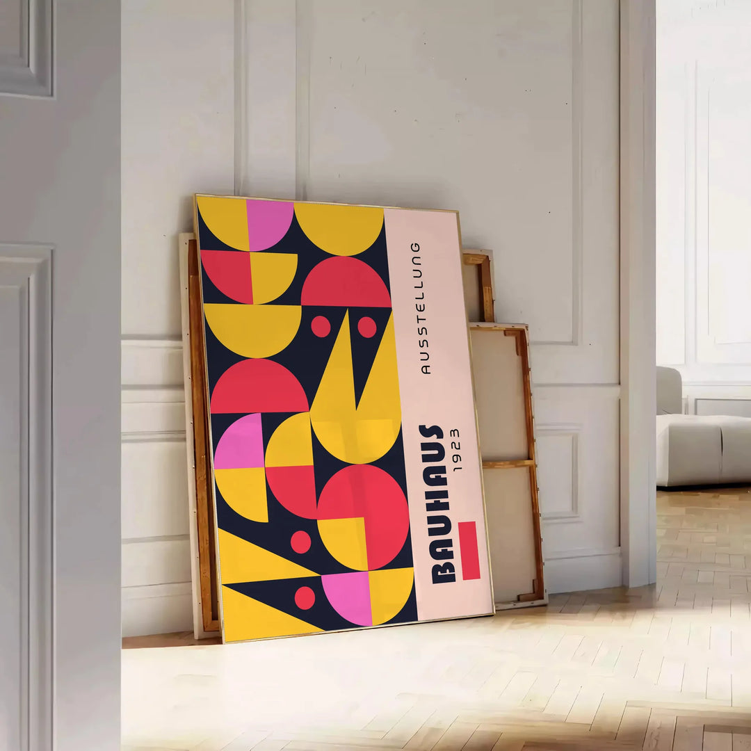 Poster showing abstract Bauhaus geometric artwork in yellow and black - leaning on a herringbone floor against a white panelled wall
