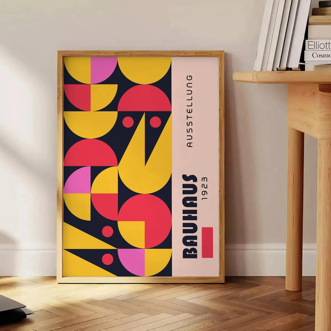 Poster showing abstract Bauhaus geometric artwork in yellow and black - beside a round wooden side table with books