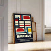 Bauhaus-Plakat mit abstrakter geometrischer Komposition in Grün und Rot - an eine weiße Paneelwand gelehnt auf Fischgrätparkett
