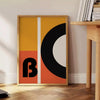 Brown and black geometric Bauhaus poster with minimalist abstract shapes - beside a round wooden side table with books