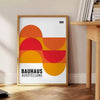Poster non incorniciato con composizione geometrica Bauhaus minimalista - accanto a un tavolino rotondo in legno con libri