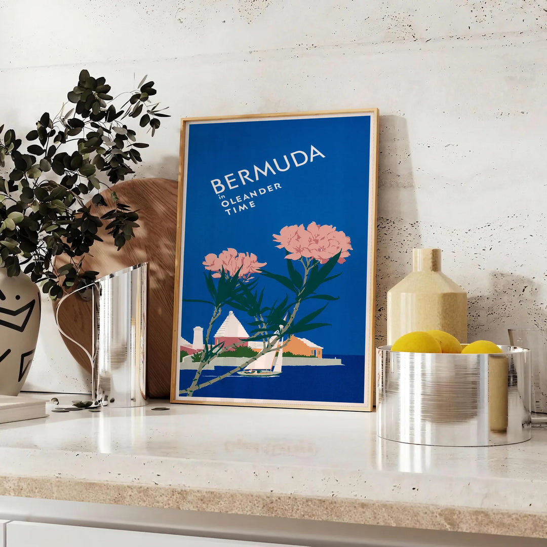 Bermuda travel poster featuring a serene beach scene with blue and green hues - styled on a counter with eucalyptus and a bowl of lemons