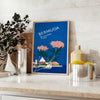 Bermuda travel poster featuring a serene beach scene with blue and green hues - styled on a counter with eucalyptus and a bowl of lemons