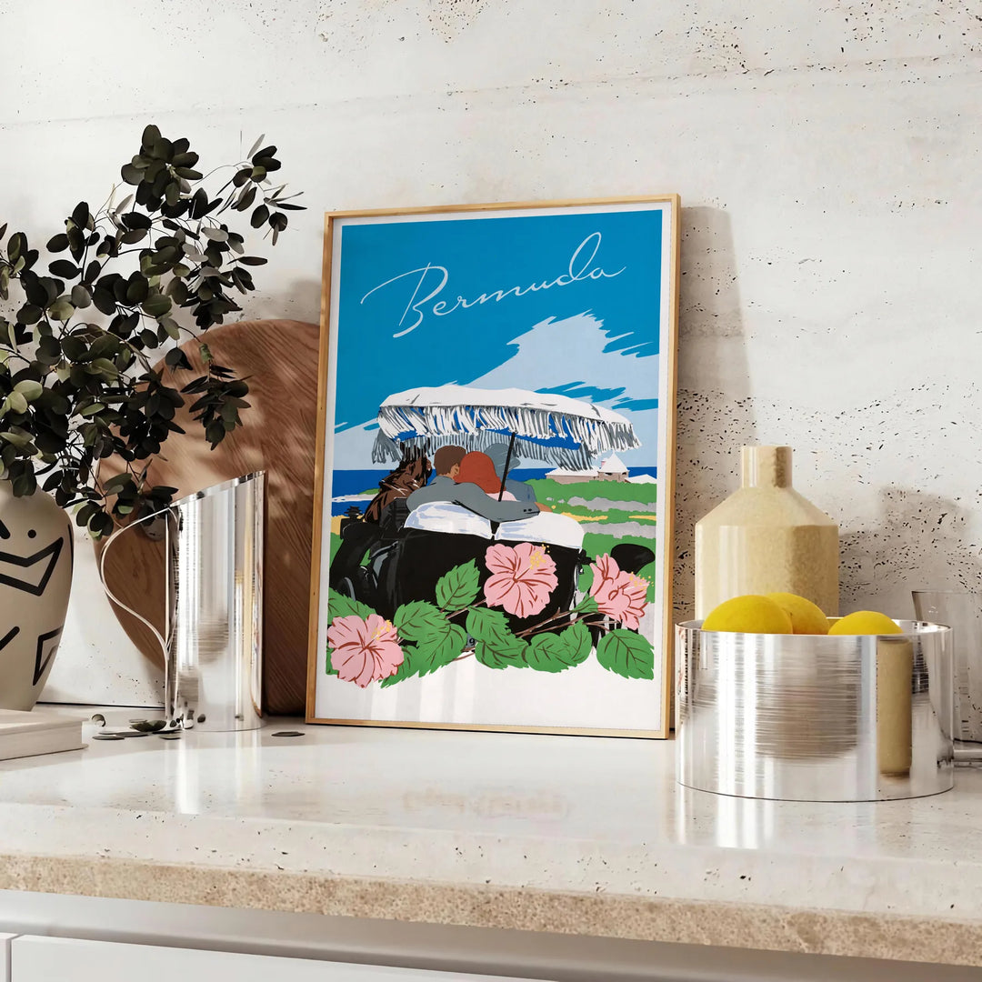A vintage travel poster featuring Bermuda's coastline in muted gray and black tones - styled on a counter with eucalyptus and a bowl of lemons