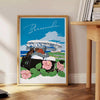 A vintage travel poster featuring Bermuda's coastline in muted gray and black tones - beside a round wooden side table with books