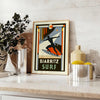 Orange and black Biarritz surf poster in retro graphic style - styled on a counter with eucalyptus and a bowl of lemons