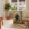 A stylized rat riding a bicycle, featuring bold black and orange colors - in a Parisian living room with a sofa and a fig plant