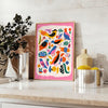 A colorful bird illustration with bold orange and blue hues - styled on a counter with eucalyptus and a bowl of lemons