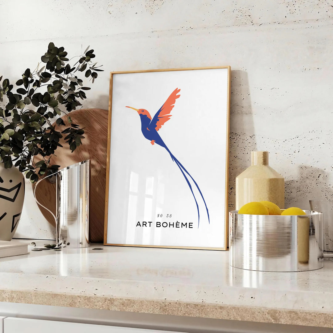 Colorful bird illustration with orange and blue hues on a dark background - styled on a counter with eucalyptus and a bowl of lemons