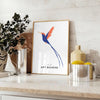 Colorful bird illustration with orange and blue hues on a dark background - styled on a counter with eucalyptus and a bowl of lemons