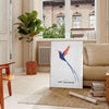 Colorful bird illustration with orange and blue hues on a dark background - in a Parisian living room with a sofa and a fig plant