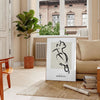 A bohemian-style poster featuring a bird in shades of gray and black - in a Parisian living room with a sofa and a fig plant