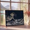 Black and white depiction of Hokusai's wave with green accents - beside a round wooden side table with books
