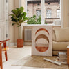 Abstract shapes in earthy browns and greens with a boho style - in a Parisian living room with a sofa and a fig plant