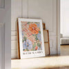 Botanical illustration featuring green leaves and orange flowers - leaning on a herringbone floor against a white panelled wall