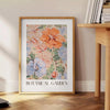 Botanical illustration featuring green leaves and orange flowers - beside a round wooden side table with books