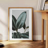 Vintage botanisches Foto mit üppigem grünem Laub vor einem ruhigen blauen Hintergrund - neben einem runden Beistelltisch aus Holz mit Büchern