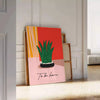 Botanical illustration featuring green leaves and orange flowers on a light background - leaning on a herringbone floor against a white panelled wall