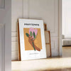 Botanical illustration featuring lush green leaves and vibrant orange flowers - leaning on a herringbone floor against a white panelled wall