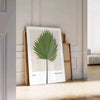 Vintage botanical illustration featuring orange and gray tones with detailed plant designs - leaning on a herringbone floor against a white panelled wall