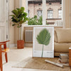 Vintage botanical illustration featuring orange and gray tones with detailed plant designs - in a Parisian living room with a sofa and a fig plant