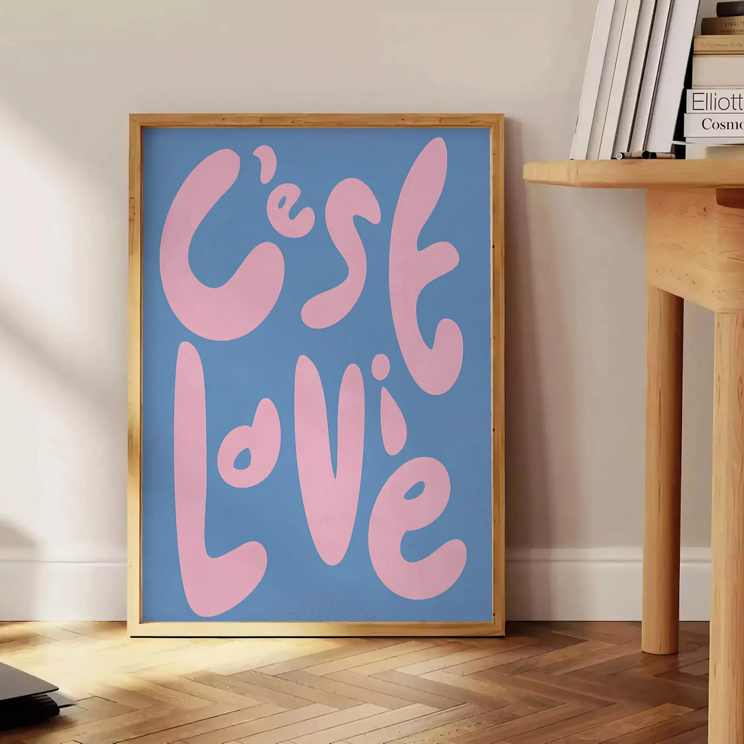 Abstract design with brown and green tones featuring the phrase 'C'est La Vie' - beside a round wooden side table with books