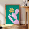 A whimsical illustration of a cactus with animal features in green and blue tones - beside a round wooden side table with books