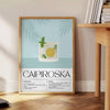 Un cocktail Caipiroska in un bicchiere su uno sfondo nero con accenti verdi - accanto a un tavolino rotondo in legno con libri