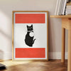 A stylized black and orange cat silhouette against a textured background - beside a round wooden side table with books
