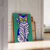 A modern art depiction of a cat in abstract shapes with green and blue tones - leaning on a herringbone floor against a white panelled wall