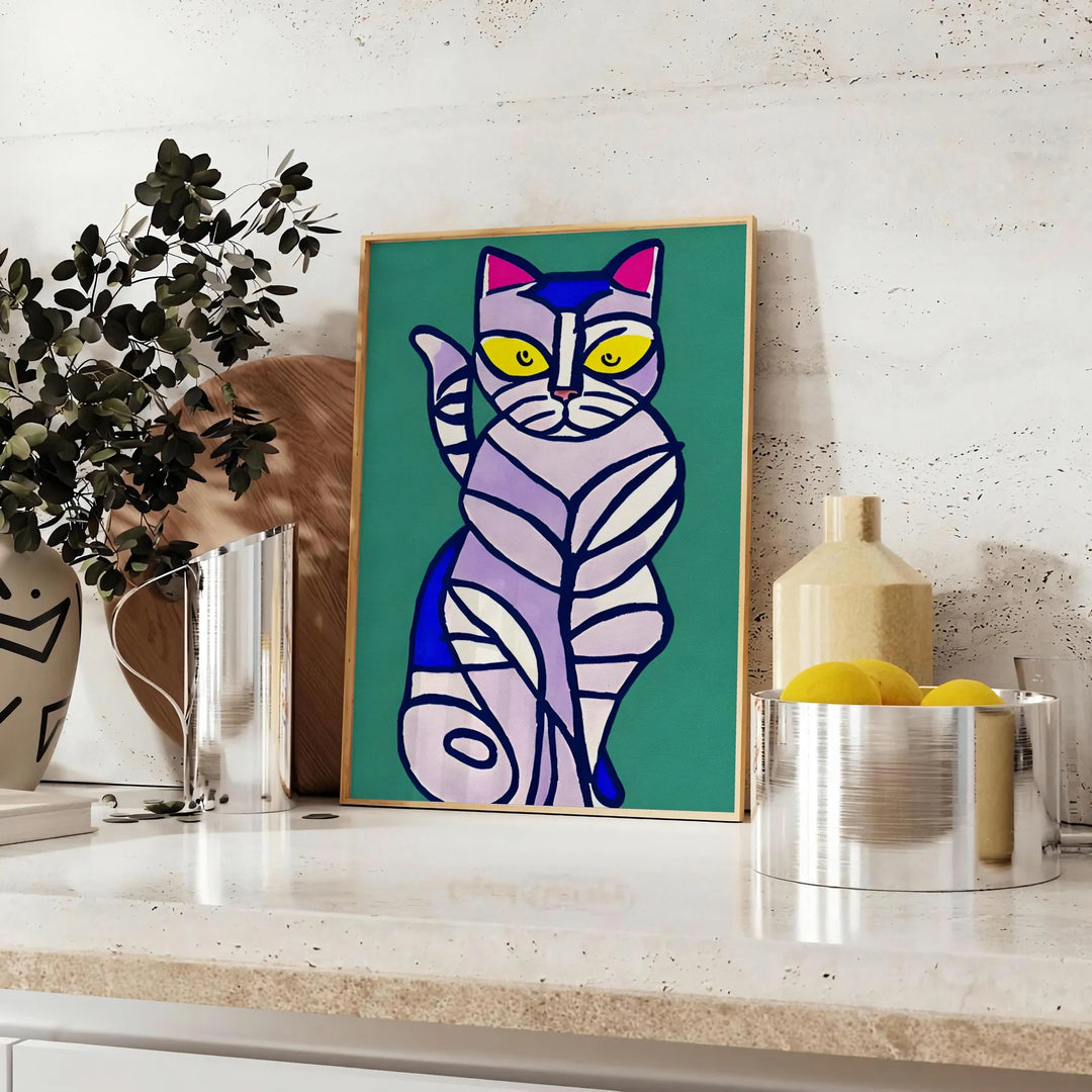 A modern art depiction of a cat in abstract shapes with green and blue tones - styled on a counter with eucalyptus and a bowl of lemons