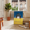 Chanel Pub Poster featuring a stylish design in gray and blue tones - in a Parisian living room with a sofa and a fig plant