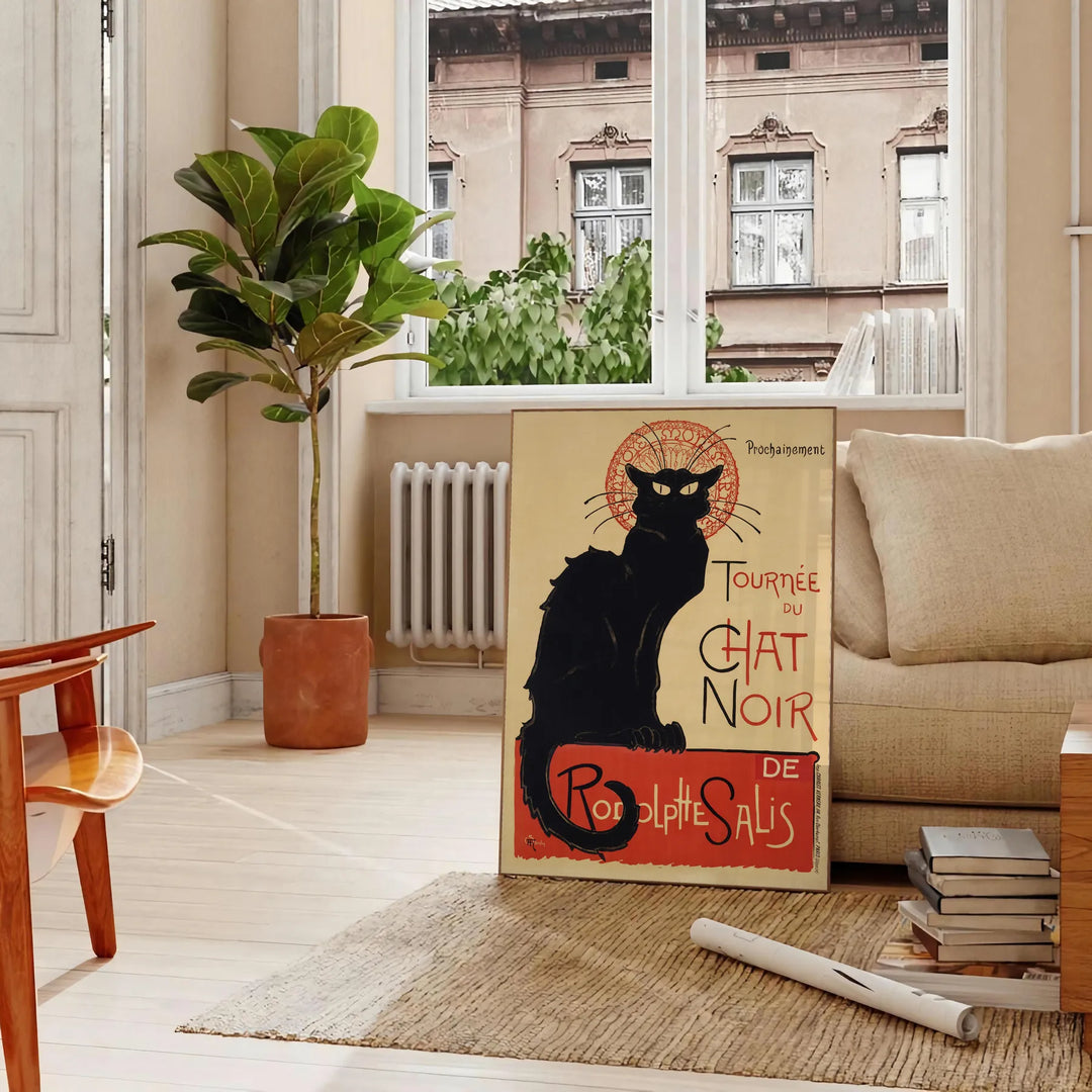 A vintage poster featuring a black cat with a yellow background, text reading 'Chat Noir'. - in a Parisian living room with a sofa and a fig plant