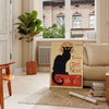 A vintage poster featuring a black cat with a yellow background, text reading 'Chat Noir'. - in a Parisian living room with a sofa and a fig plant