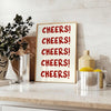 シンプルなデザインで「Cheers」の文字がグレーとホワイトで表現されています - ユーカリとレモンのボウルを添えたカウンターに