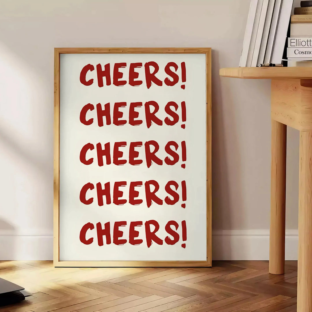 シンプルなデザインで「Cheers」の文字がグレーとホワイトで表現されています - 本を置いた丸い木製サイドテーブルの横に