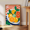 A kitchen scene featuring citrus fruits in bright orange and blue tones - beside a round wooden side table with books