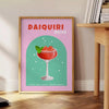 Uma ilustração colorida de um coquetel daiquiri com tons verdes e laranjas - ao lado de uma mesa de apoio redonda em madeira com livros