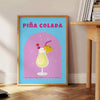 Affiche vibrante teintes marron orange exotisme cocktail Piña Colada espace cadeau une version cadre œuvre unique - à côté d'une table d'appoint ronde en bois avec des livres
