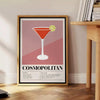 Cocktail cosmopolita in un bicchiere su uno sfondo cosmico - accanto a un tavolino rotondo in legno con libri