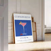 A stylish illustration of a cosmopolitan cocktail against a blue backdrop - leaning on a herringbone floor against a white panelled wall