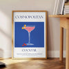A stylish illustration of a cosmopolitan cocktail against a blue backdrop - beside a round wooden side table with books