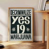 Vintage poster featuring bold black and orange design advocating marijuana decriminalization - beside a round wooden side table with books