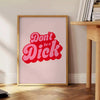 Colorful retro-style poster with the phrase 'Don't Be A Dick' in bold letters - beside a round wooden side table with books