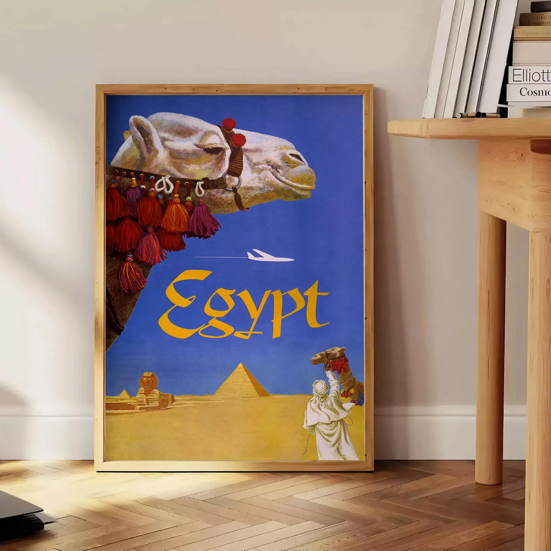 Poster di viaggio che rappresenta l'Egitto con tonalità blu e grigie - accanto a un tavolino rotondo in legno con libri