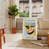 A colorful illustration of spicy noodles in a bowl with chopsticks, featuring yellow and green tones - in a Parisian living room with a sofa and a fig plant