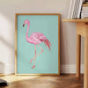A pink flamingo standing gracefully against a black and orange background - beside a round wooden side table with books